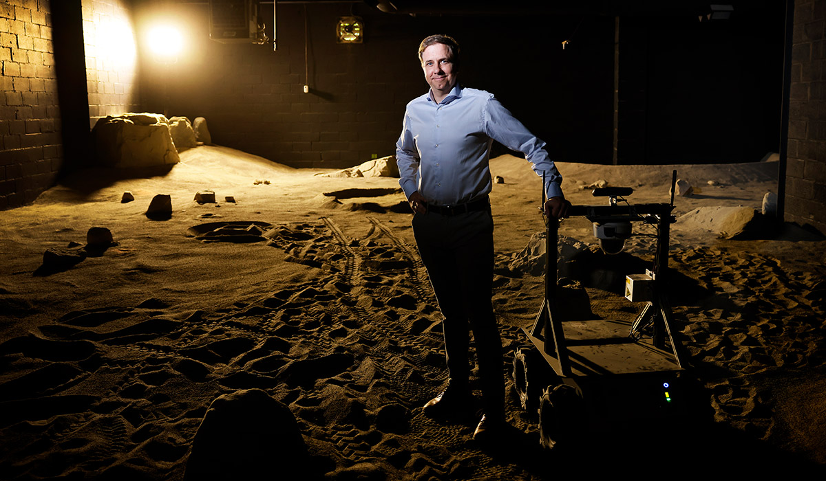 Ewan Reid stands next to a planetary rover