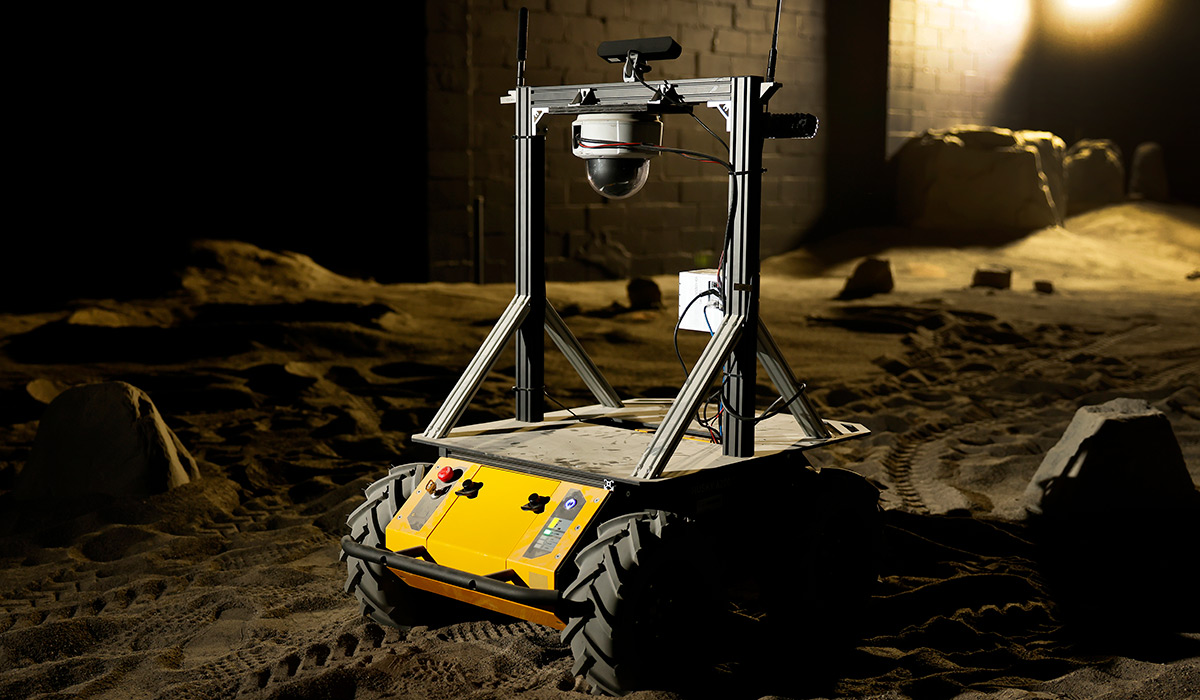A yellow planetary rover sitting on sand
