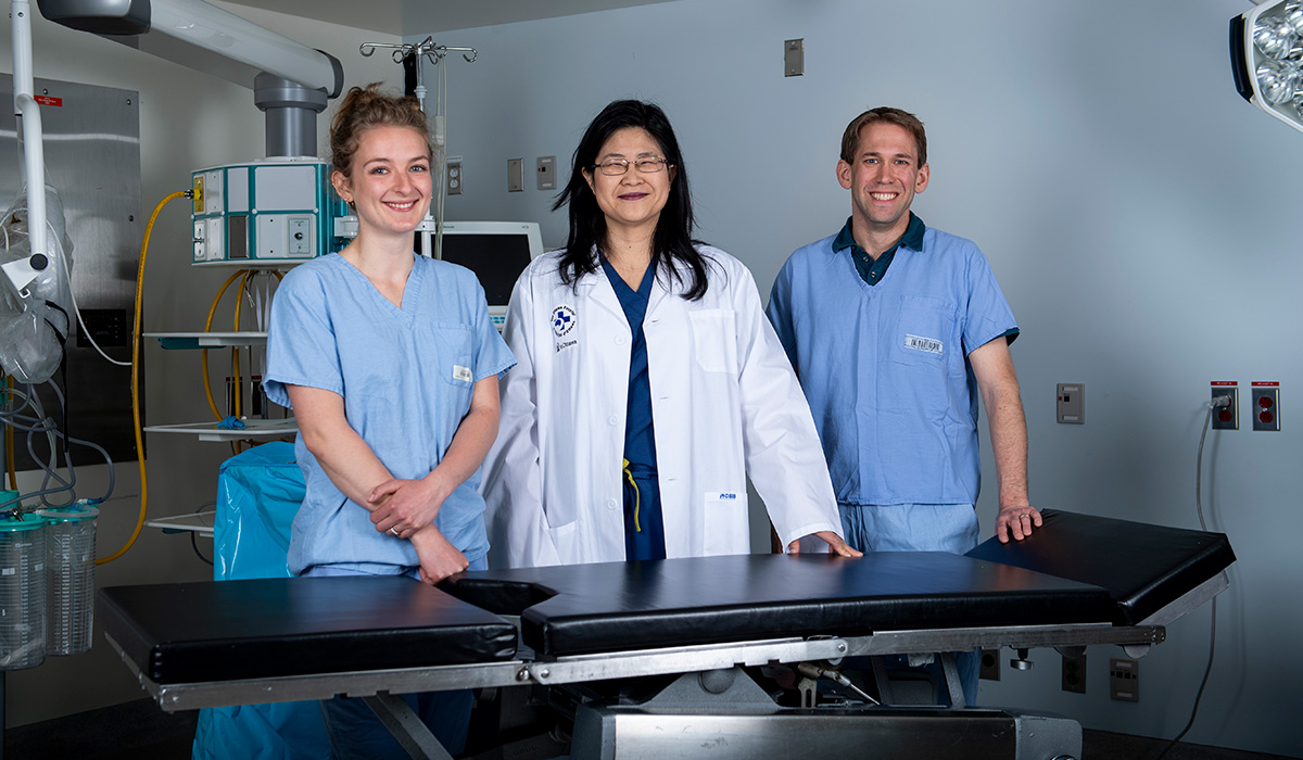 Three medical professionals posing for a photo in an operating room.