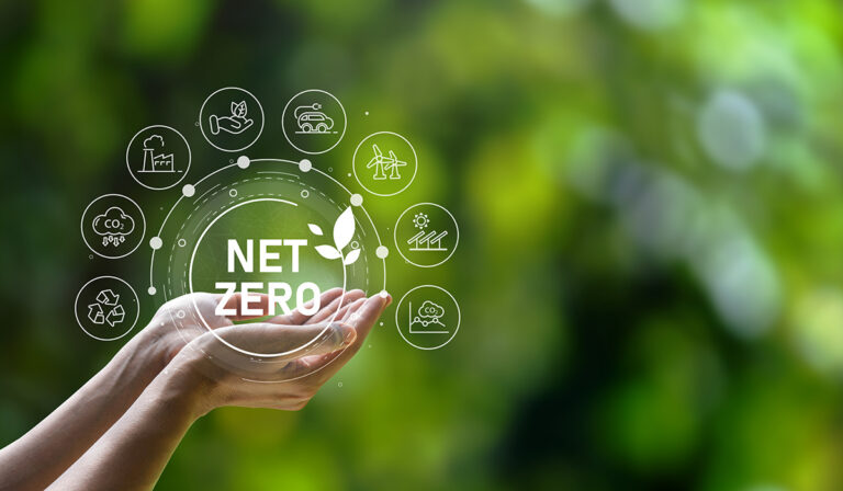 A design concept representing carbon neutrality and net-zero. A hand holds a net-zero icon which is surrounded by other smaller icons representing emissions targets.