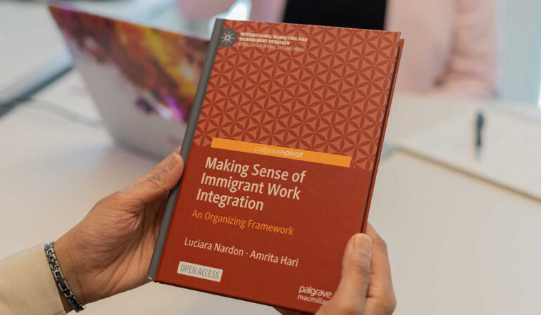 A person holds a book titled Making Sense of Immigrant Work Integration