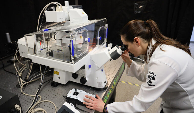 A scientist peers into the lens of a high-powered microscope